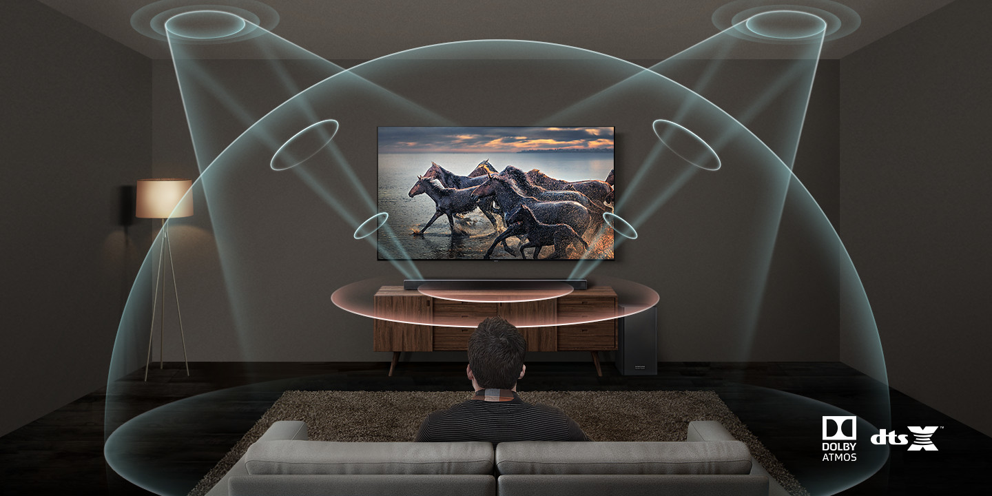 A person sits on a couch in a modern living room, watching horses run on a TV. Sound waves from a soundbar surround the viewer, illustrating immersive Dolby Atmos and DTS:X audio technology.