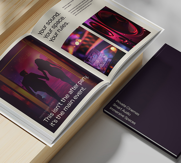 A photo shows an open book with colorful images of people at an event and text about sound and parties. Next to it lies a closed dark purple book titled Private Cinemas Smart Audio Immersive Spaces on a light wooden surface.