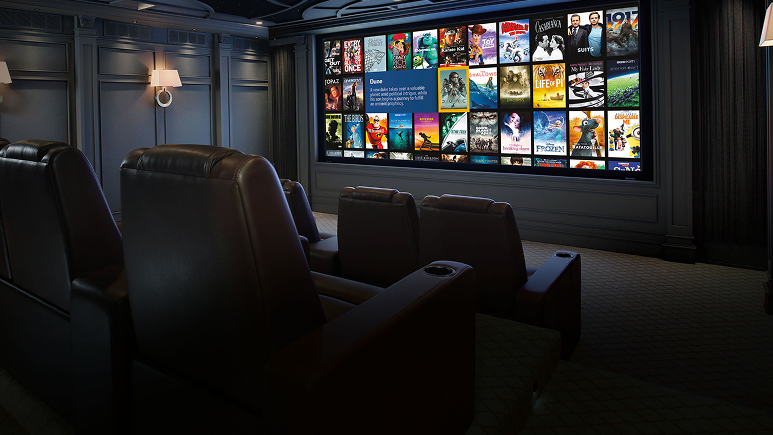 A luxurious Home Cinemas theater room with black leather recliners faces a large screen displaying movie posters and streaming options, all set against paneled dark walls with modern wall sconces.